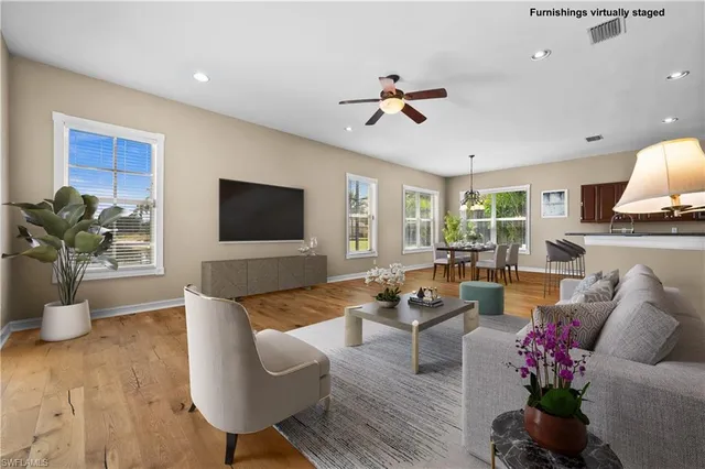 a living room with couches and kitchen view with wooden floor