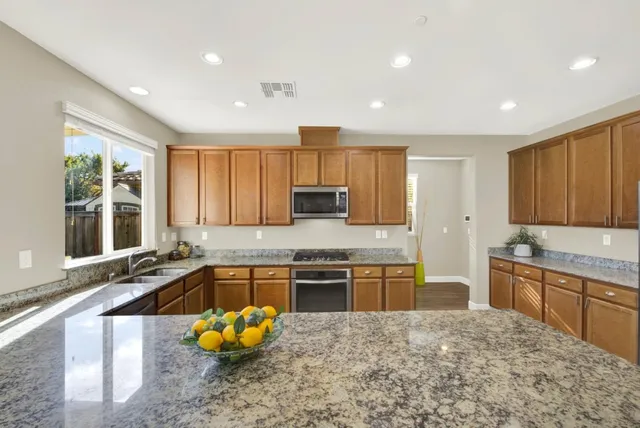 a large kitchen with kitchen island granite countertop wooden cabinets a granite counter top and stainless steel appliances