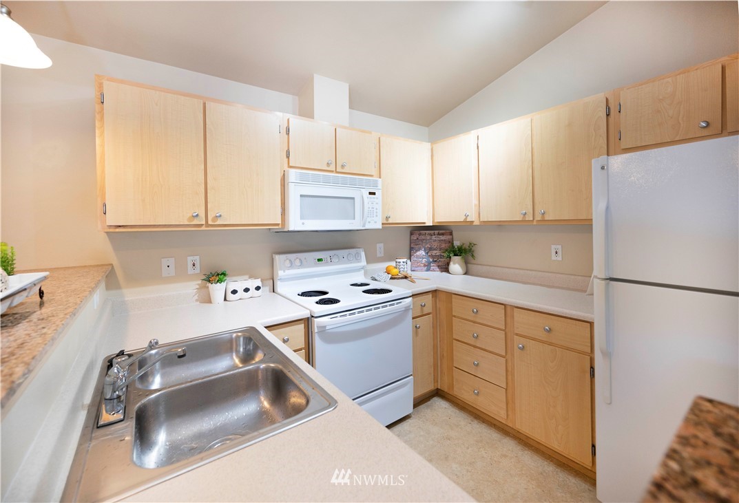 10709 Valley View Road, Unit A301 Bothell, WA 98011 - Photo 11 of 26 a kitchen with a sink a stove a refrigerator and white cabinets