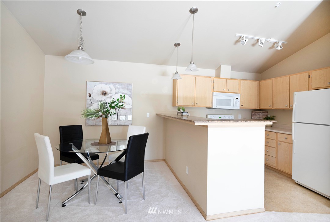 10709 Valley View Road, Unit A301 Bothell, WA 98011 - Photo 9 of 26 a dining room filled chandelier and kitchen view