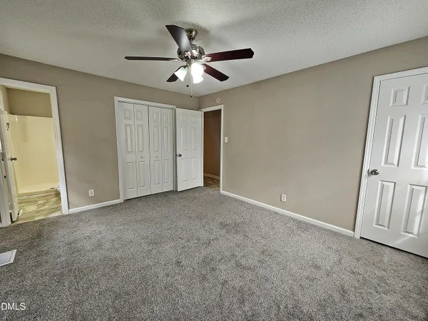 an empty room with a window and a fan