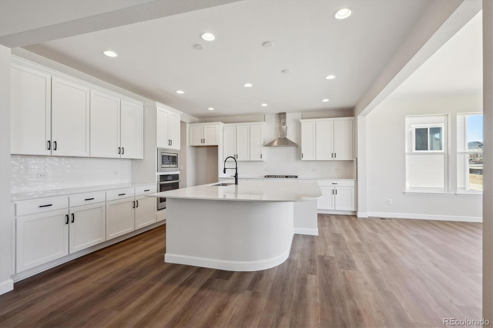 5583 Riverbend Avenue Firestone, CO 80504 - Photo 9 of 25 a large kitchen with stainless steel appliances a large counter top a wooden floors and white cabinets