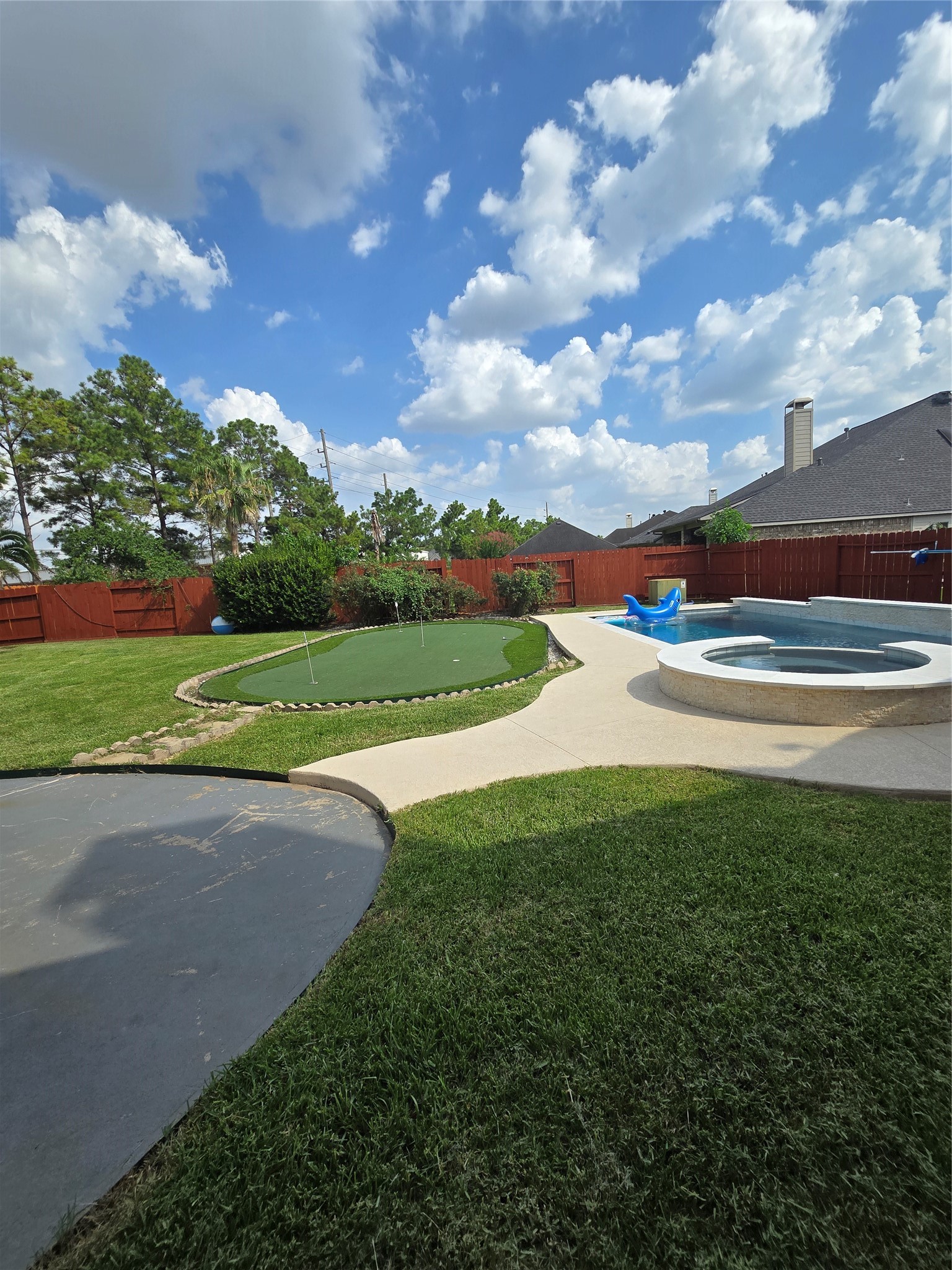 6506 Monte Bello Ridge Lane Houston, TX 77041 - Photo 33 of 39 Spacious backyard featuring a well-maintained lawn, a putting green, and a circular spa, perfect for outdoor relaxation and entertainment.