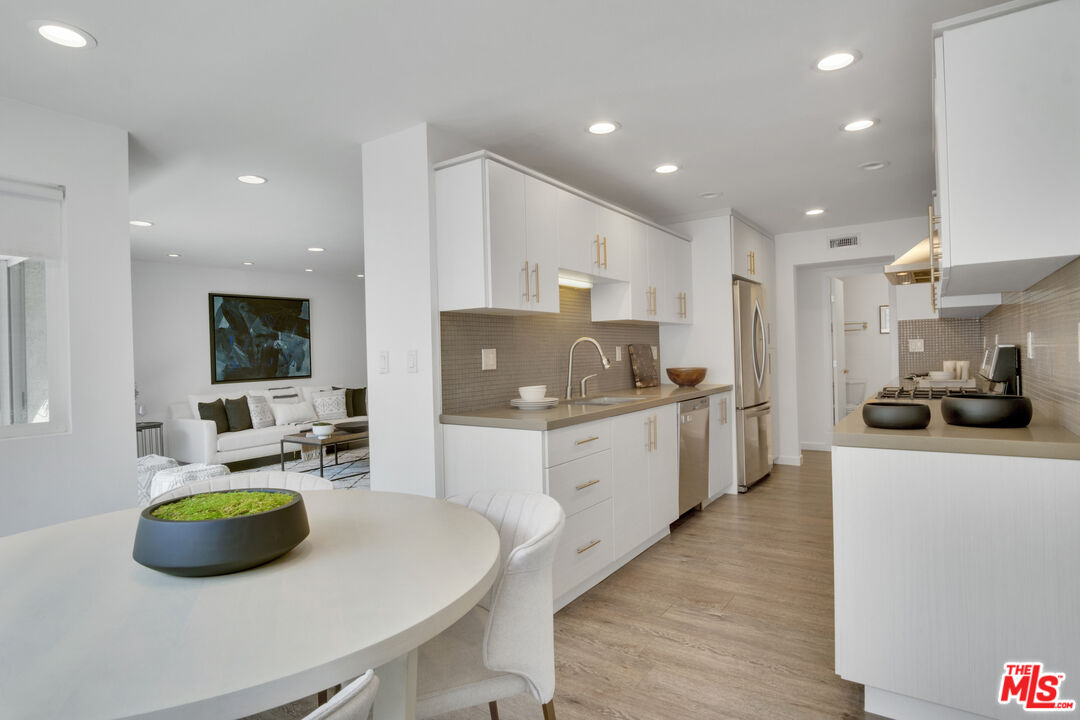 a kitchen with stainless steel appliances a sink a microwave a refrigerator and white cabinets