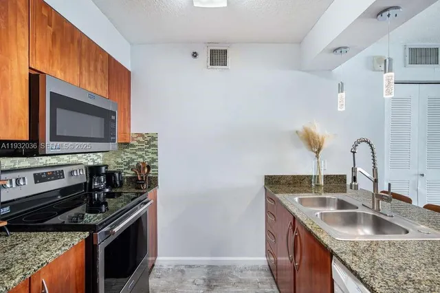 a kitchen with granite countertop a sink stove and microwave