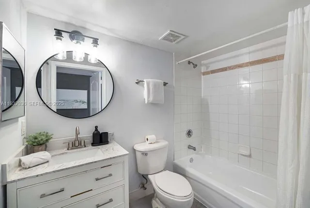 a bathroom with a toilet a sink a mirror a bathtub and shower