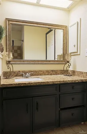 a bathroom with a granite countertop sink and a mirror