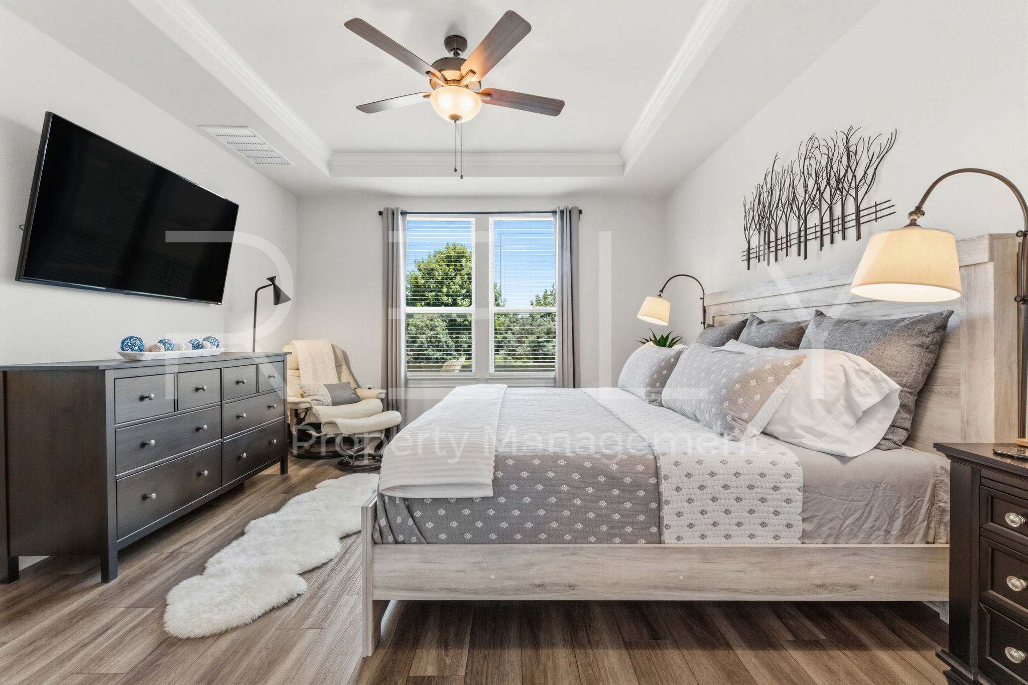 101 Spanish Star Street Georgetown, TX 78633 - Photo 24 of 39 A generous bedroom features wood-look flooring and a tray ceiling, enhancing its spacious appeal.