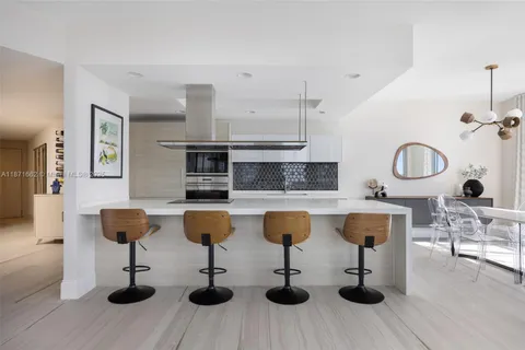a view of kitchen with stainless steel appliances kitchen island granite countertop a table and chairs in it