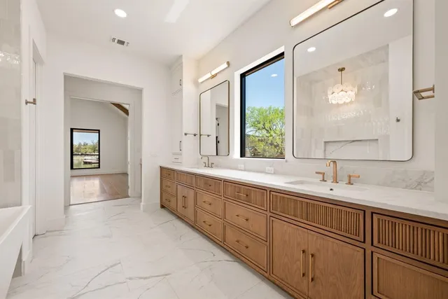 a spacious bathroom with double sink large mirror and a window