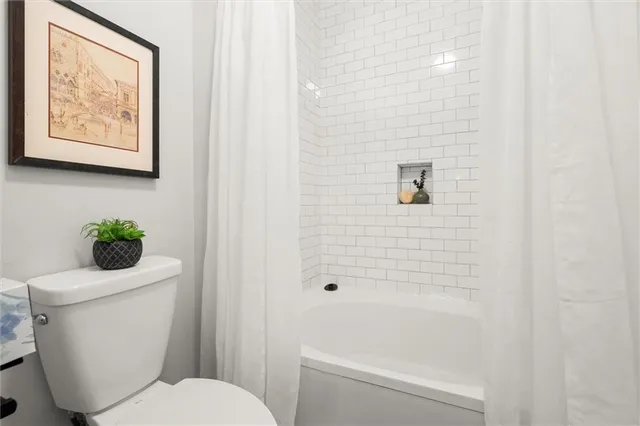 a white toilet sitting next to a bath tub