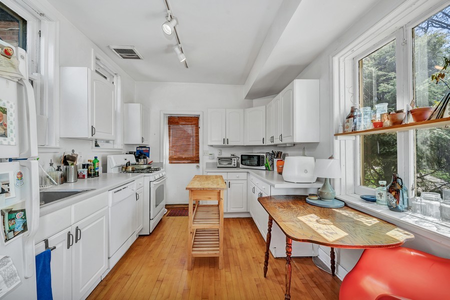 4249 North Hazel Street Chicago, IL 60613 - Photo 6 of 14 a kitchen with stainless steel appliances granite countertop a stove top oven a sink dishwasher a dining table and chairs with wooden floor