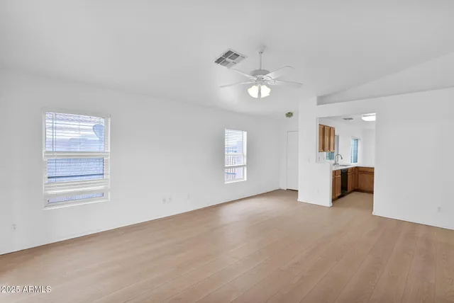 an empty room with windows and chandelier fan