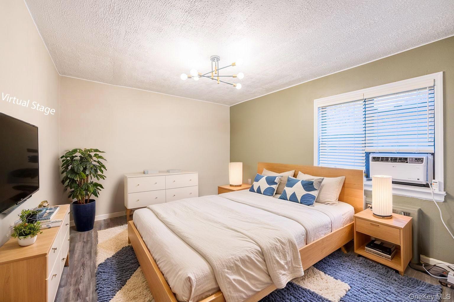 220-16 73rd Avenue, Unit 13A2 Queens, NY 11364 - Photo 3 of 18 a bedroom with furniture and a flat screen tv