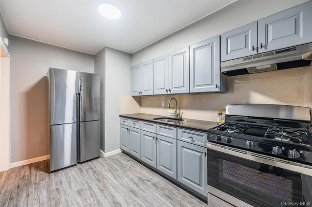 a kitchen with granite countertop a refrigerator stove top oven and cabinets