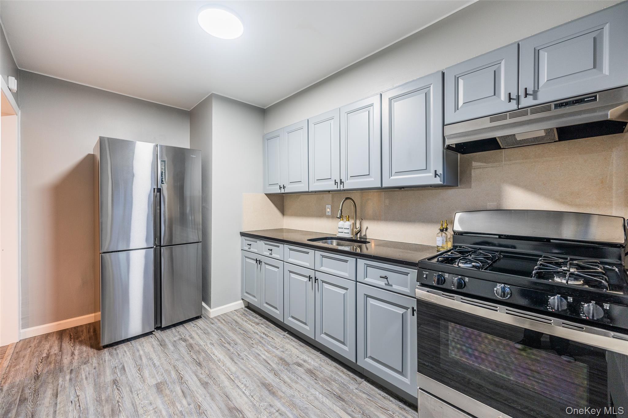 220-16 73rd Avenue, Unit 13A2 Queens, NY 11364 - Photo 8 of 18 a kitchen with granite countertop a refrigerator stove top oven and cabinets