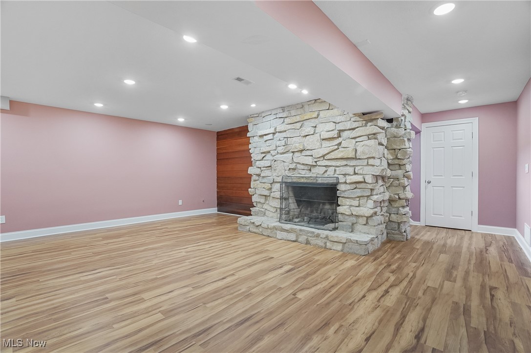 1094 San Raphael Drive Akron, OH 44333 - Photo 38 of 50 Unfurnished living room with light wood-type flooring, recessed lighting, a stone fireplace, wood walls, and an accent wall