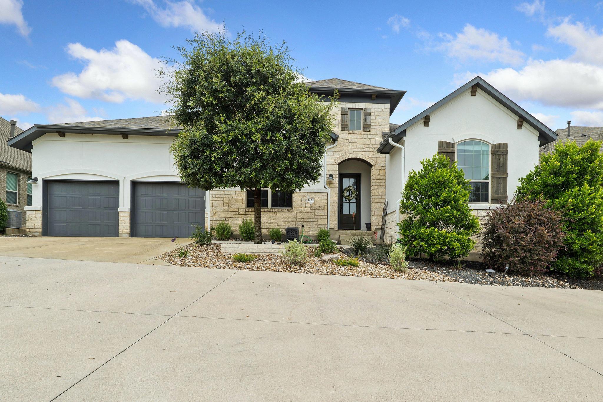 1009 Legacy Crossing Georgetown, TX 78628 - Photo 1 of 40 A striking contemporary residence boasts a stone and stucco facade, complemented by an attached garage and thoughtfully designed landscaping.