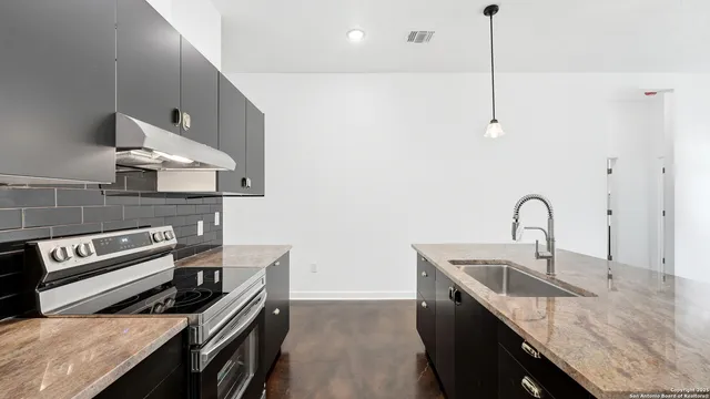 a kitchen with a sink a refrigerator and chairs
