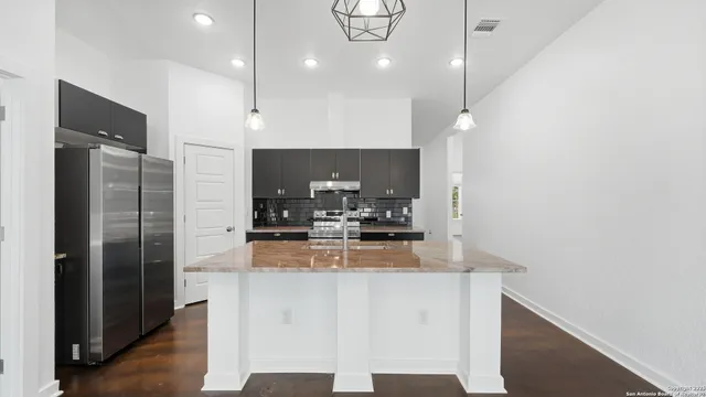 a large kitchen with stainless steel appliances granite countertop a refrigerator a oven and a sink