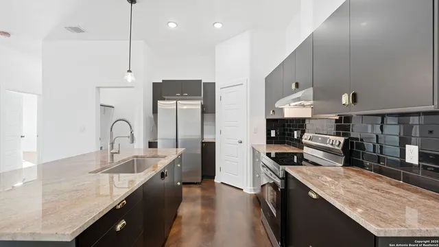 a kitchen with stainless steel appliances granite countertop a refrigerator a sink dishwasher and a oven with wooden floor