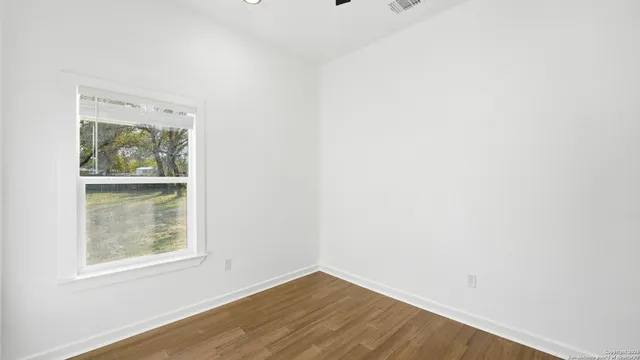 an empty room with wooden floor and a window