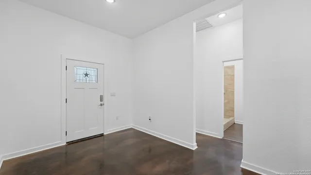 an empty room with wooden floor ceiling fan and windows