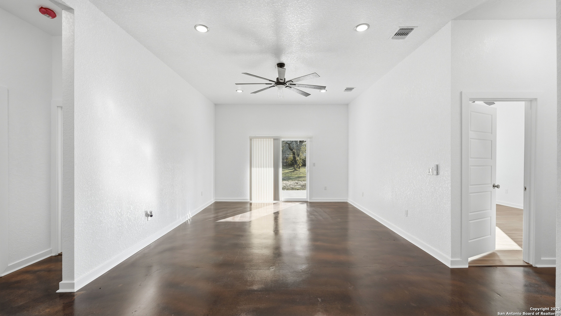4606 Lee Way Elmendorf, TX 78112 - Photo 7 of 45 an empty room with wooden floor ceiling fan and windows