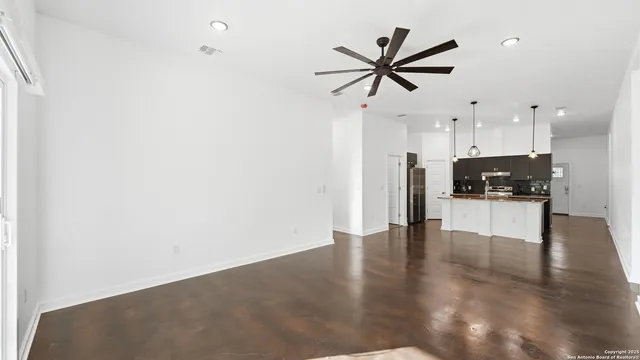 an empty room with wooden floor and a kitchen view