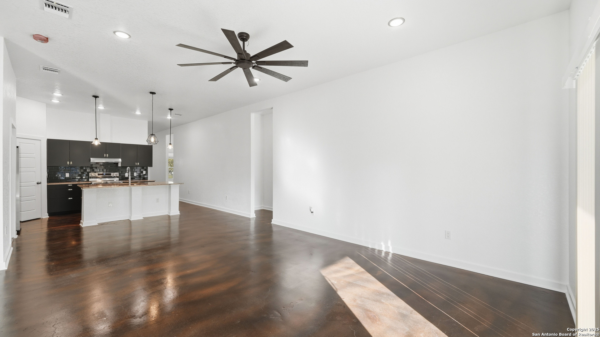 4606 Lee Way Elmendorf, TX 78112 - Photo 10 of 45 an empty room with wooden floor and a kitchen view