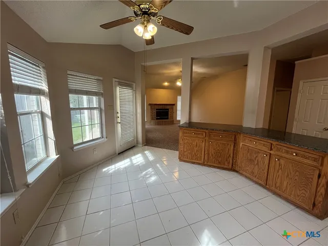 a large kitchen with a large counter top stainless steel appliances a chandelier and living room view