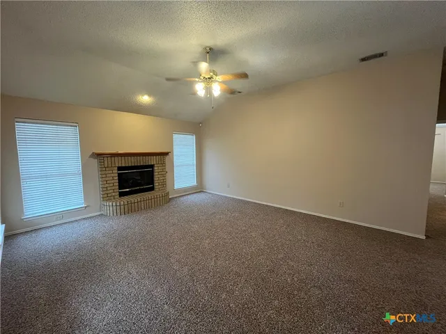 an empty room with windows fireplace and a sink