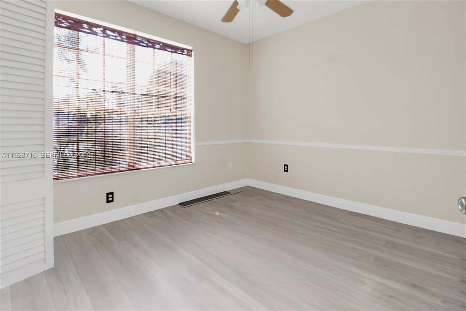 15875 Southwest 149th Lane Miami, FL 33196 - Photo 20 of 32 a view of an empty room with wooden floor and a window