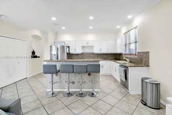 a large kitchen with granite countertop white cabinets and stainless steel appliances