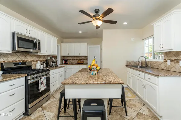 a kitchen with granite countertop kitchen island stainless steel appliances a stove sink microwave and cabinets