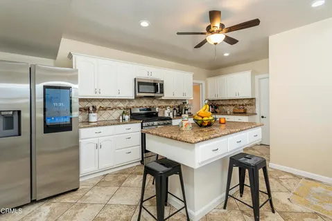 a kitchen with stainless steel appliances a stove a refrigerator a sink a stove with white cabinets and wooden floor