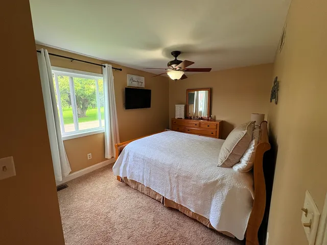 a bedroom with a bed a window and a flat screen tv