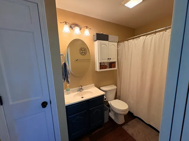 a bathroom with a granite countertop toilet a sink and a mirror