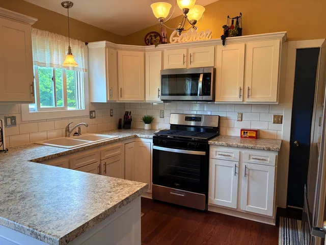 a kitchen with stainless steel appliances granite countertop a stove a sink and a microwave