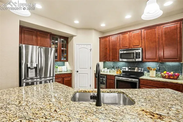 a kitchen with stainless steel appliances granite countertop a refrigerator stove top oven and sink