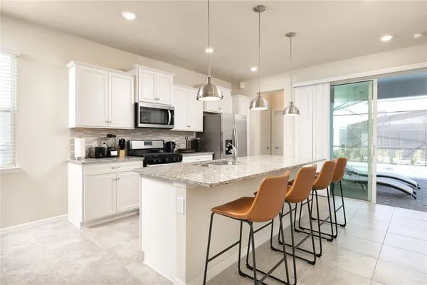 a kitchen with stainless steel appliances granite countertop a stove a sink a microwave a dining table and chairs