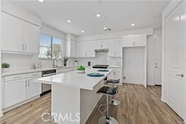 a kitchen with a sink a stove a refrigerator and white cabinets with wooden floor