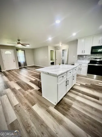a large white kitchen with kitchen island a sink stainless steel appliances and cabinets