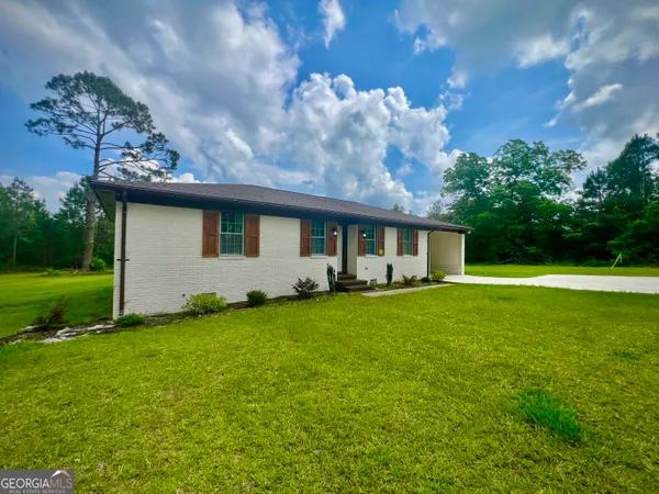 a backyard of a house with table and chairs plants and large tree