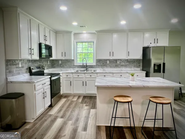 a kitchen with stainless steel appliances granite countertop a white cabinets and a refrigerator