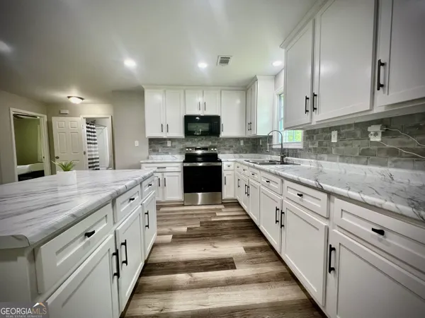 a large kitchen with stainless steel appliances granite countertop a stove a sink and a granite counter tops
