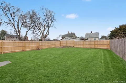 a view of green field with fence in front of house