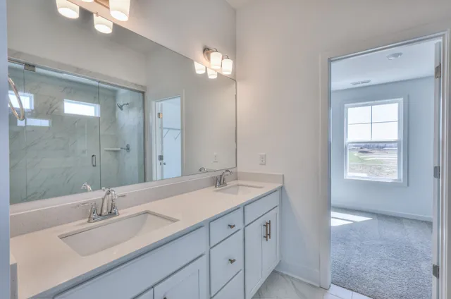 a bathroom with a sink double vanity granite tub and a mirror