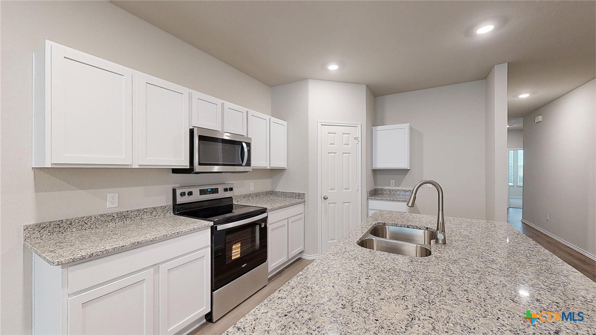 1110 Stone Vly Road Temple, TX 76502 - Photo 6 of 21 a kitchen with granite countertop stainless steel appliances a stove sink and microwave