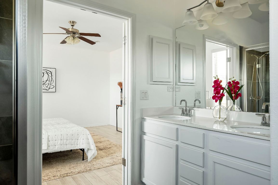 800 Totis Road Austin, TX 78748 - Photo 17 of 29 Bathroom featuring double vanity, a shower with door, light wood-type flooring, and a ceiling fan